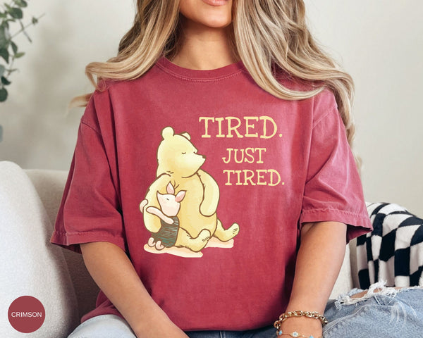 a woman sitting on a couch wearing a t - shirt that says tired just tired