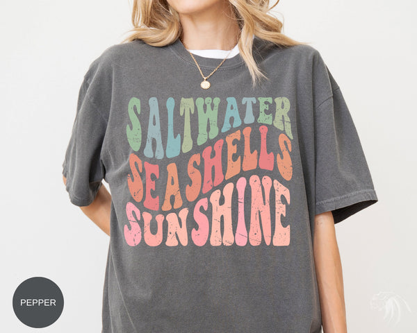 a woman wearing a t - shirt that says saltwater seashells sunshine