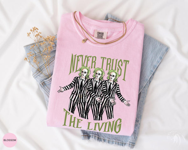 a pink t - shirt with the words never trust the living on it